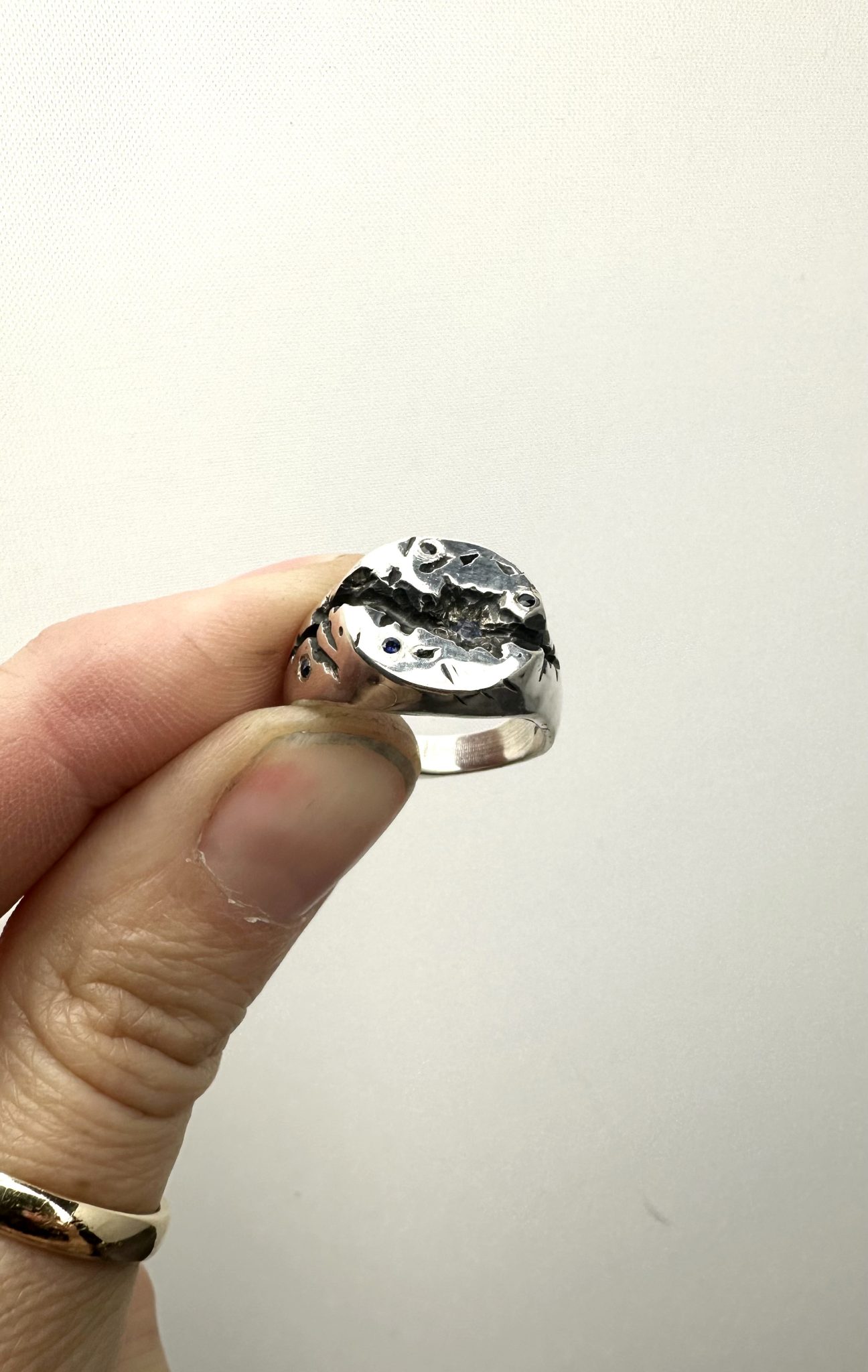 A sterling silver round signet ring, with a deep crevise handcared and scattered with sapphires.