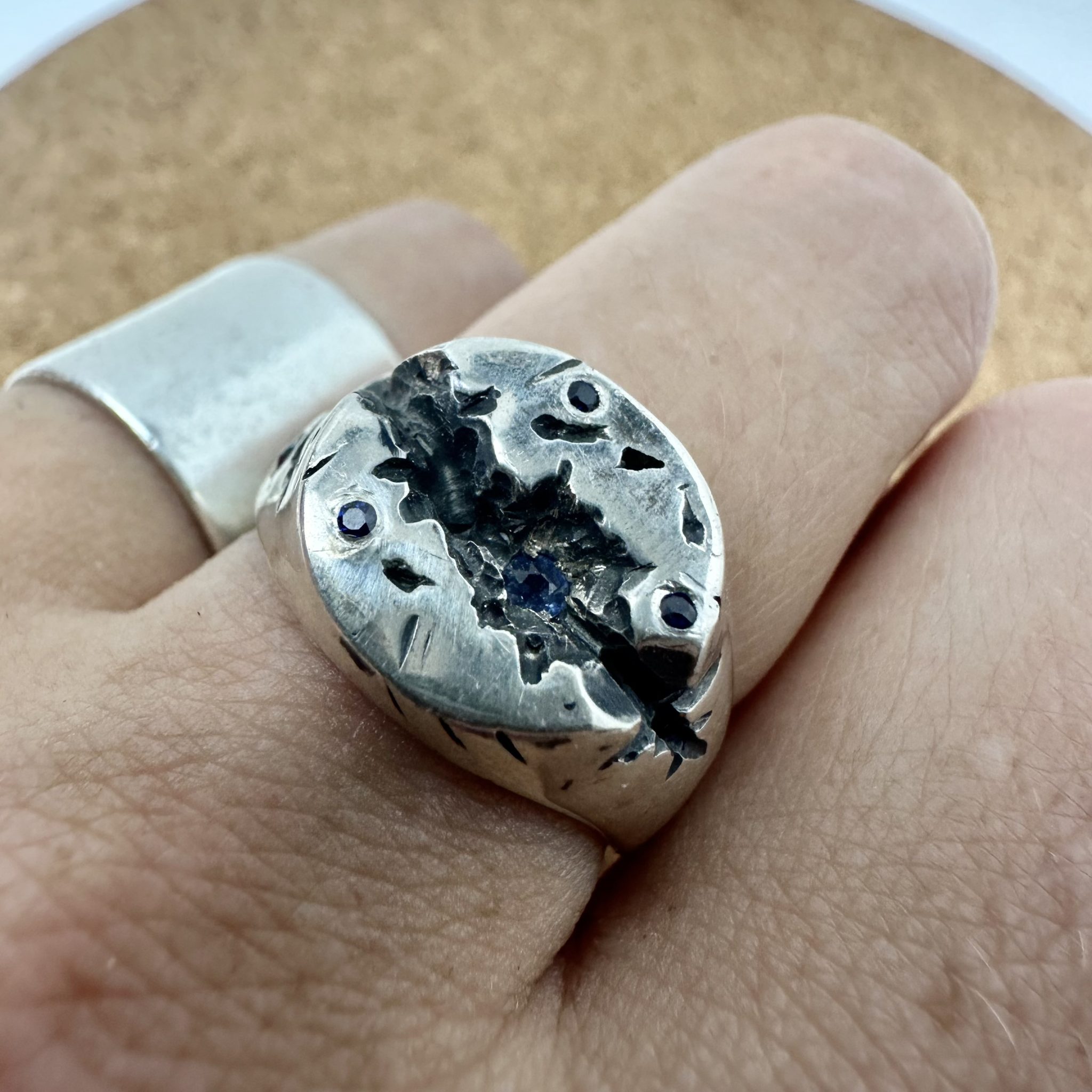 A sterling silver round signet ring, with a deep crevise handcared and scattered with sapphires.
