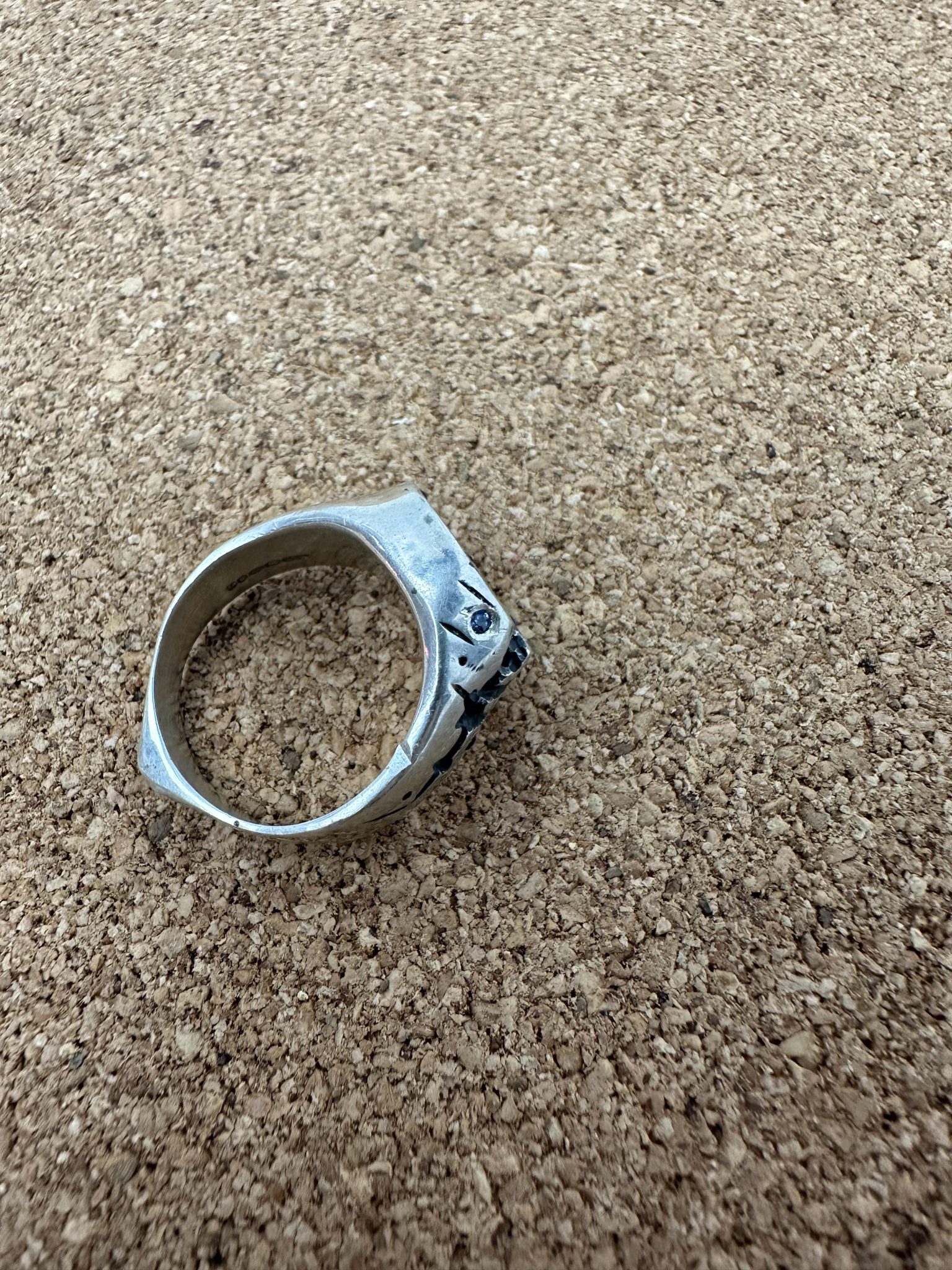 A sterling silver round signet ring, with a deep crevise handcared and scattered with sapphires.