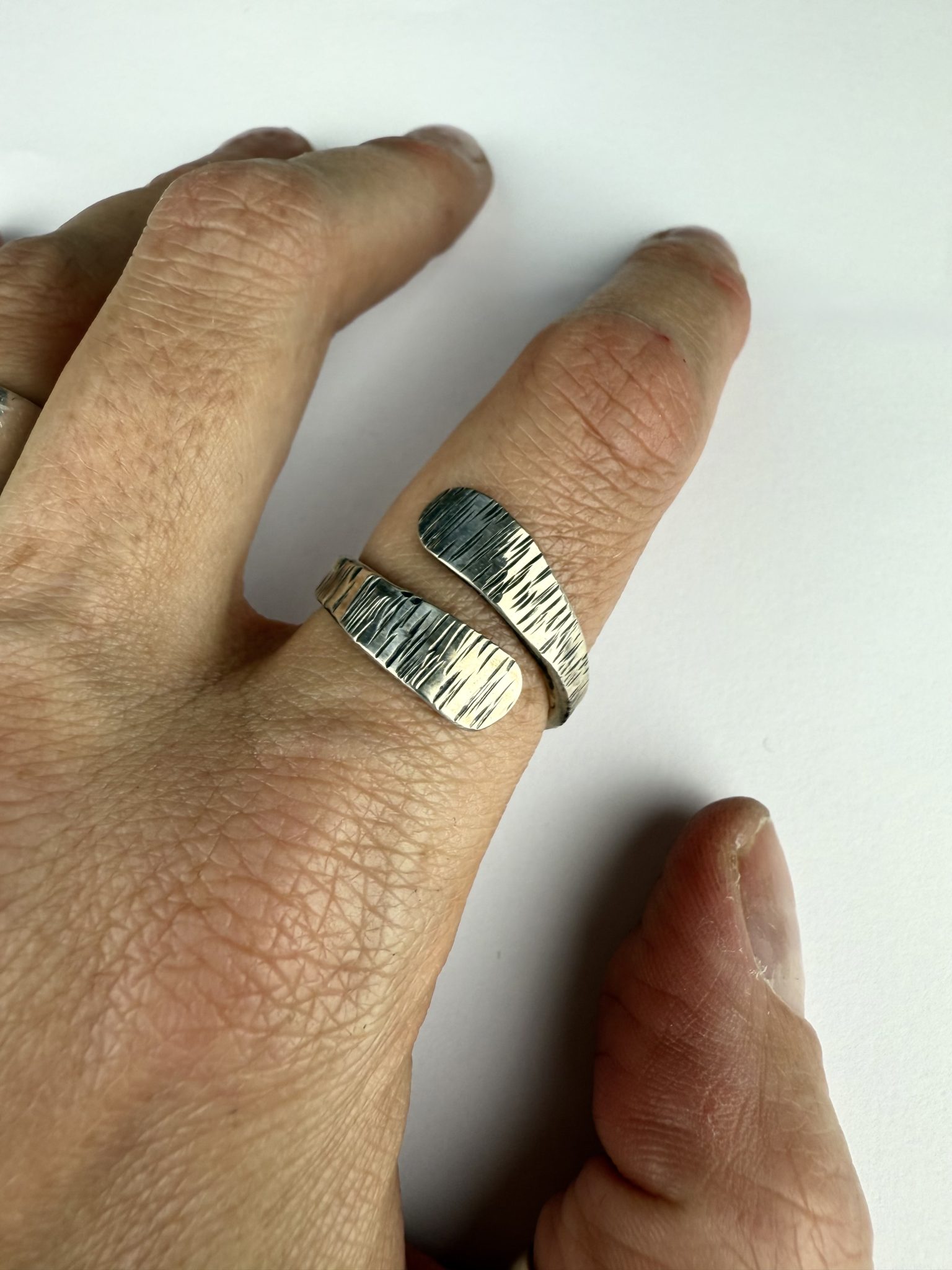 A hand forged open band sterling silver, textured wrap ring.