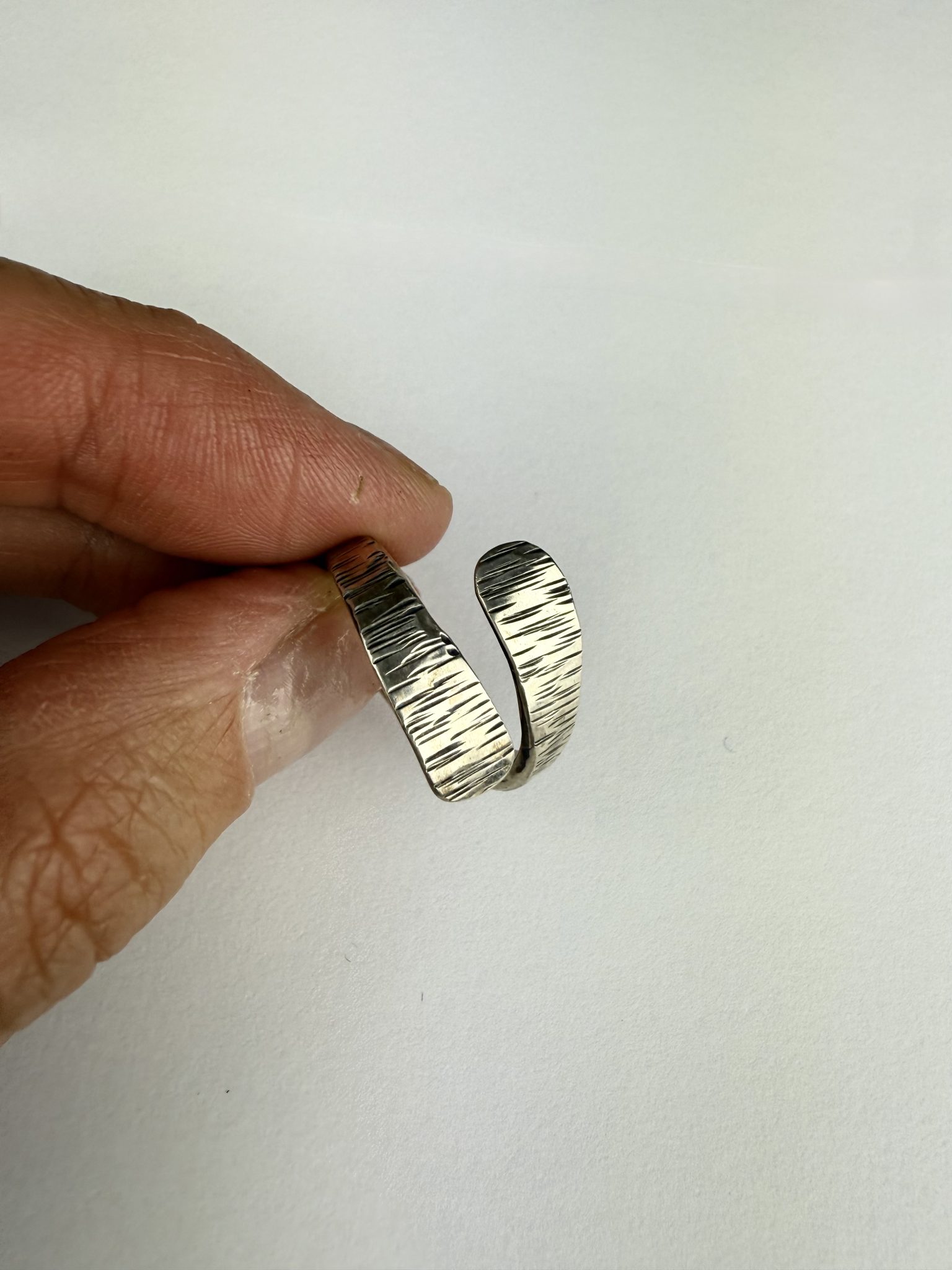 A hand forged open band sterling silver, textured wrap ring.