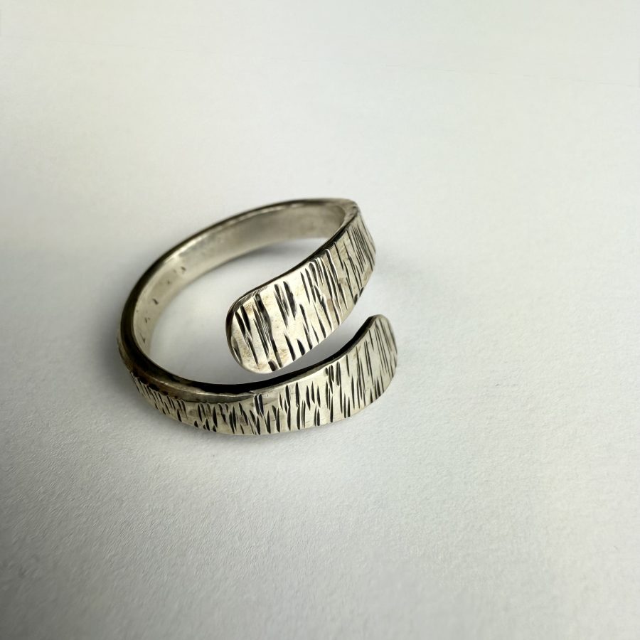 A hand forged open band sterling silver, textured wrap ring.
