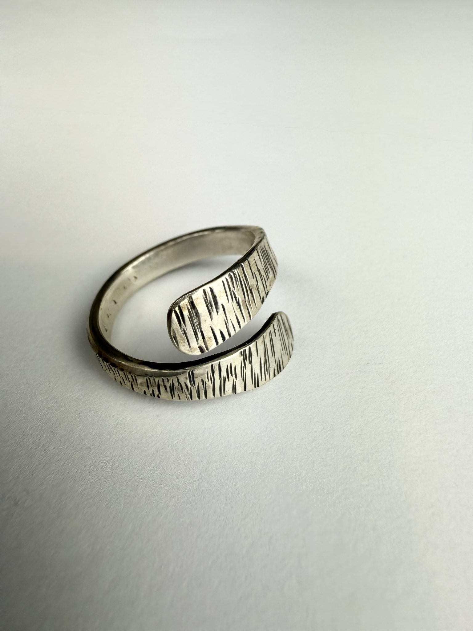 A hand forged open band sterling silver, textured wrap ring.